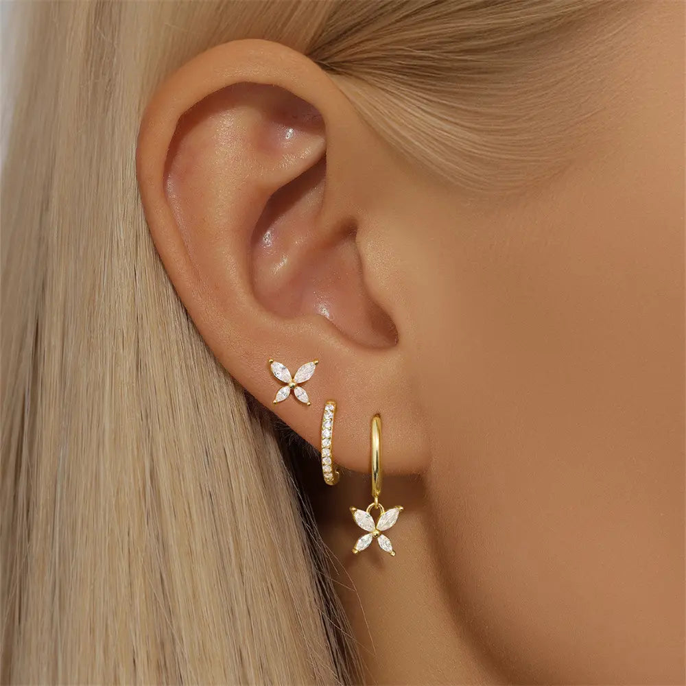 A close-up of a model's ear showcasing the gold butterfly stud and hoop earrings set with cubic zirconia stones. The dangling butterfly charm adds elegance.