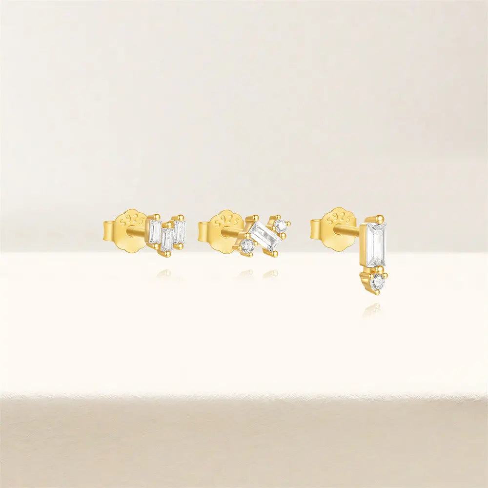 Set of three gold stud earrings with baguette and round-cut crystals, crafted in 925 sterling silver, displayed on a clean neutral background for a modern and elegant look.