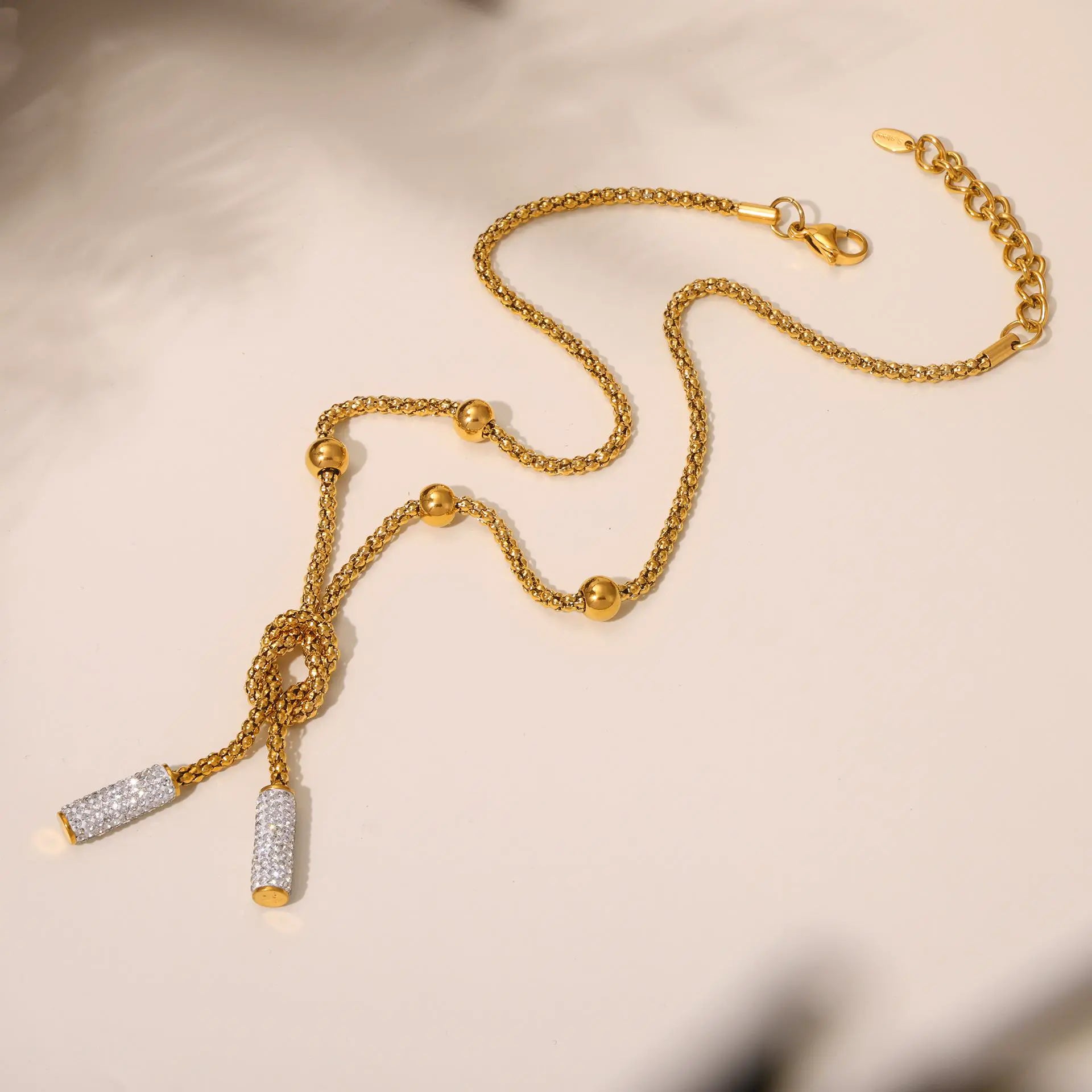 Full view of a gold chain necklace with spherical beads and a knot design, featuring an adjustable clasp for versatile wear.