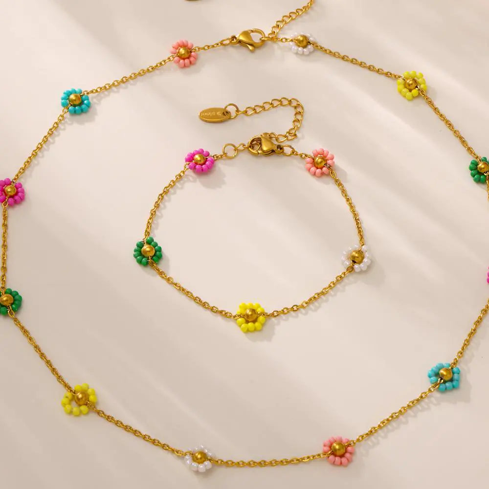 Matching set of gold chain necklace and bracelet adorned with vibrant beaded flower accents.