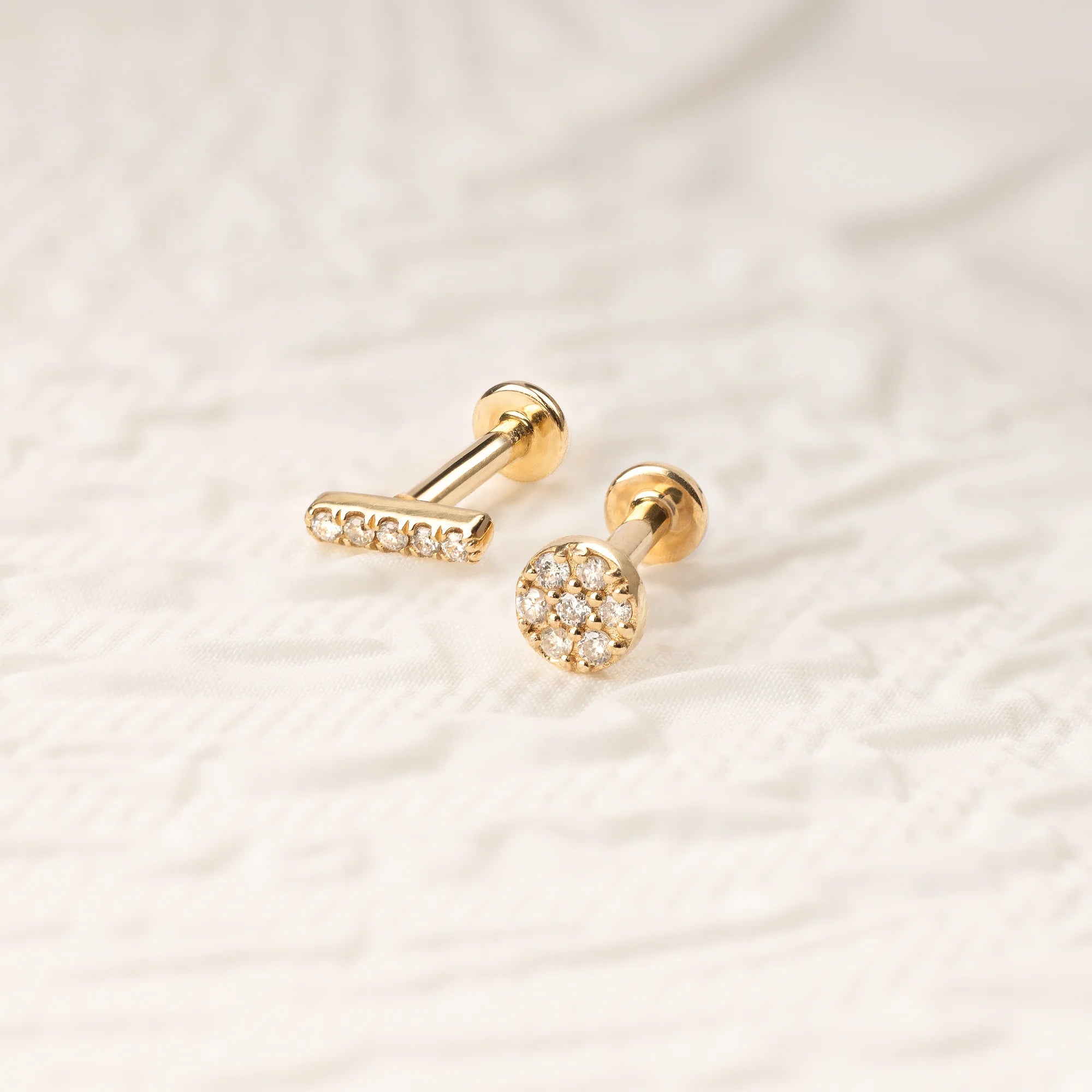 A stylish pair of 14K gold zircon stud earrings, including a bar and floral design.