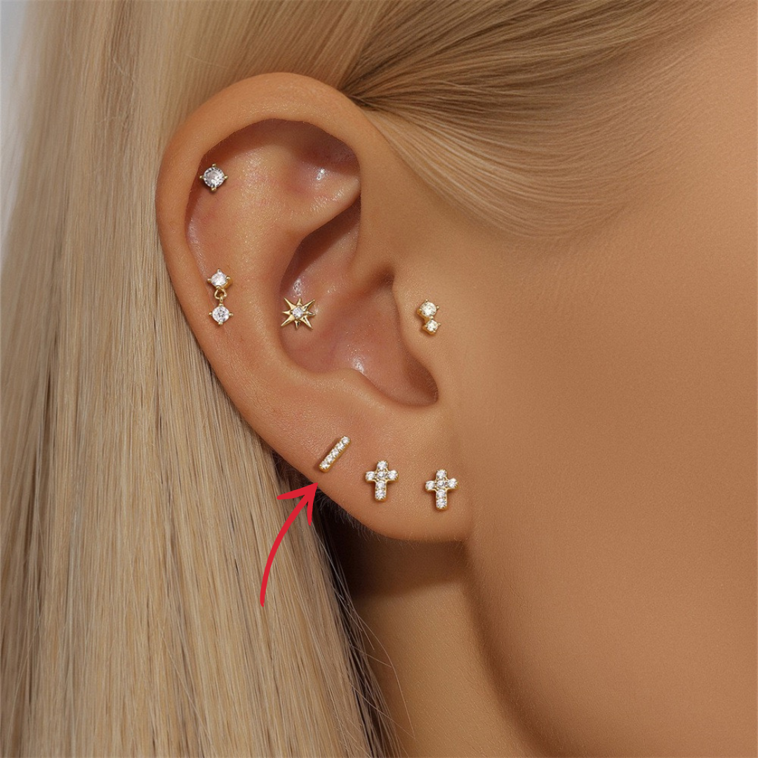 Woman wearing a delicate 14K gold bar stud earring with zircon stones.