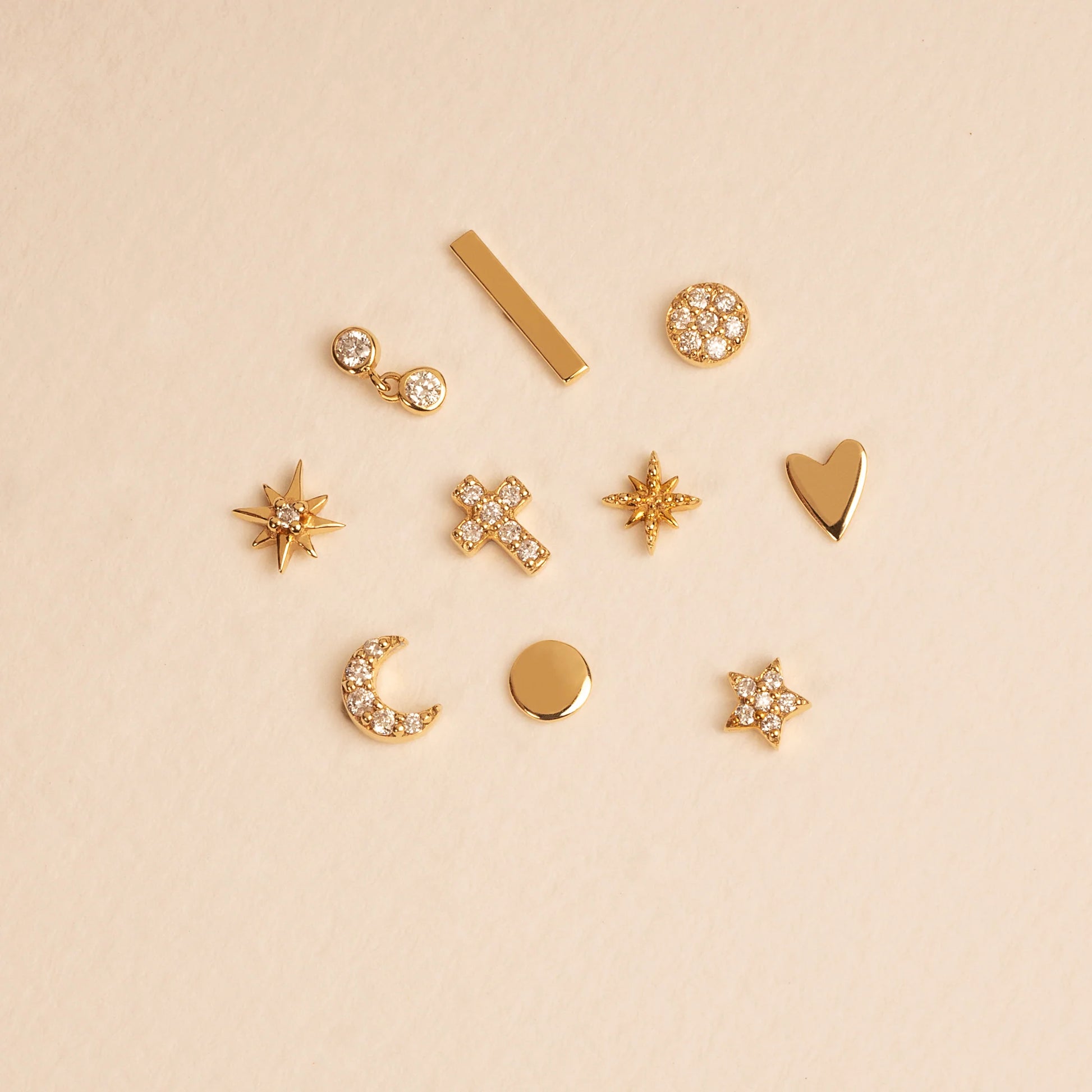 A collection of 14K gold earrings featuring stars, crosses, moons, and minimalist designs.