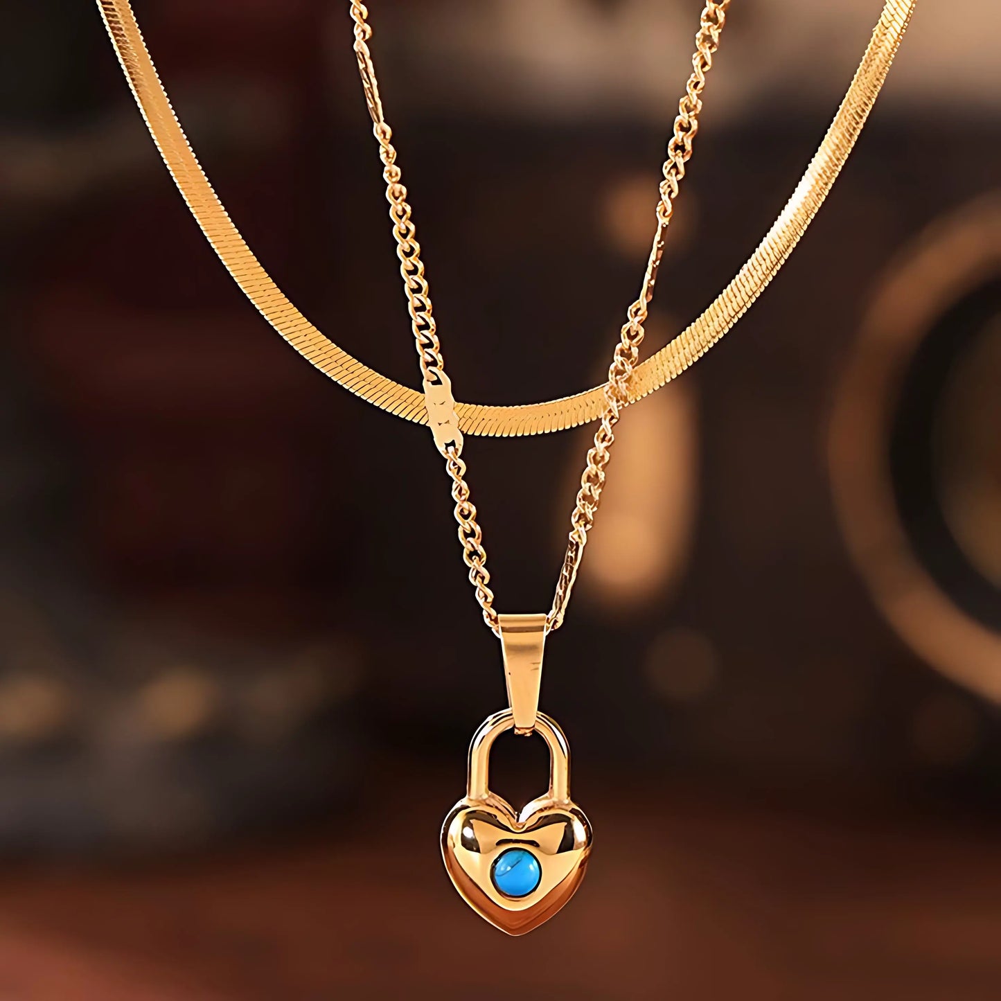 Close-up of a 14k gold heart-shaped padlock pendant necklace featuring a turquoise stone, displayed on a model.