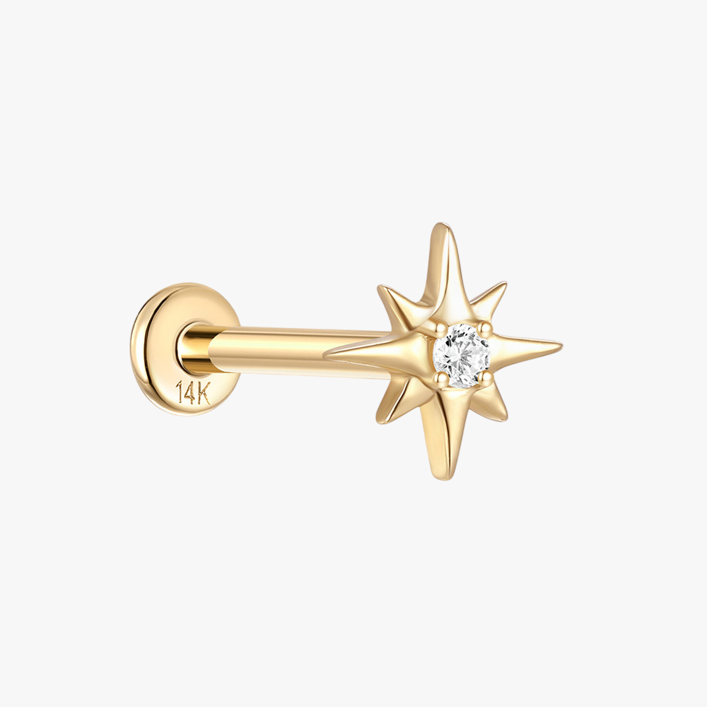 Close-up of a 14K gold north star stud earring with a sparkling zircon center.