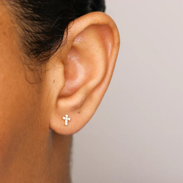 Model wearing 14K gold-plated cross-shaped stud earrings adorned with zirconia stones, showing off a stylish and minimalist ear stack.