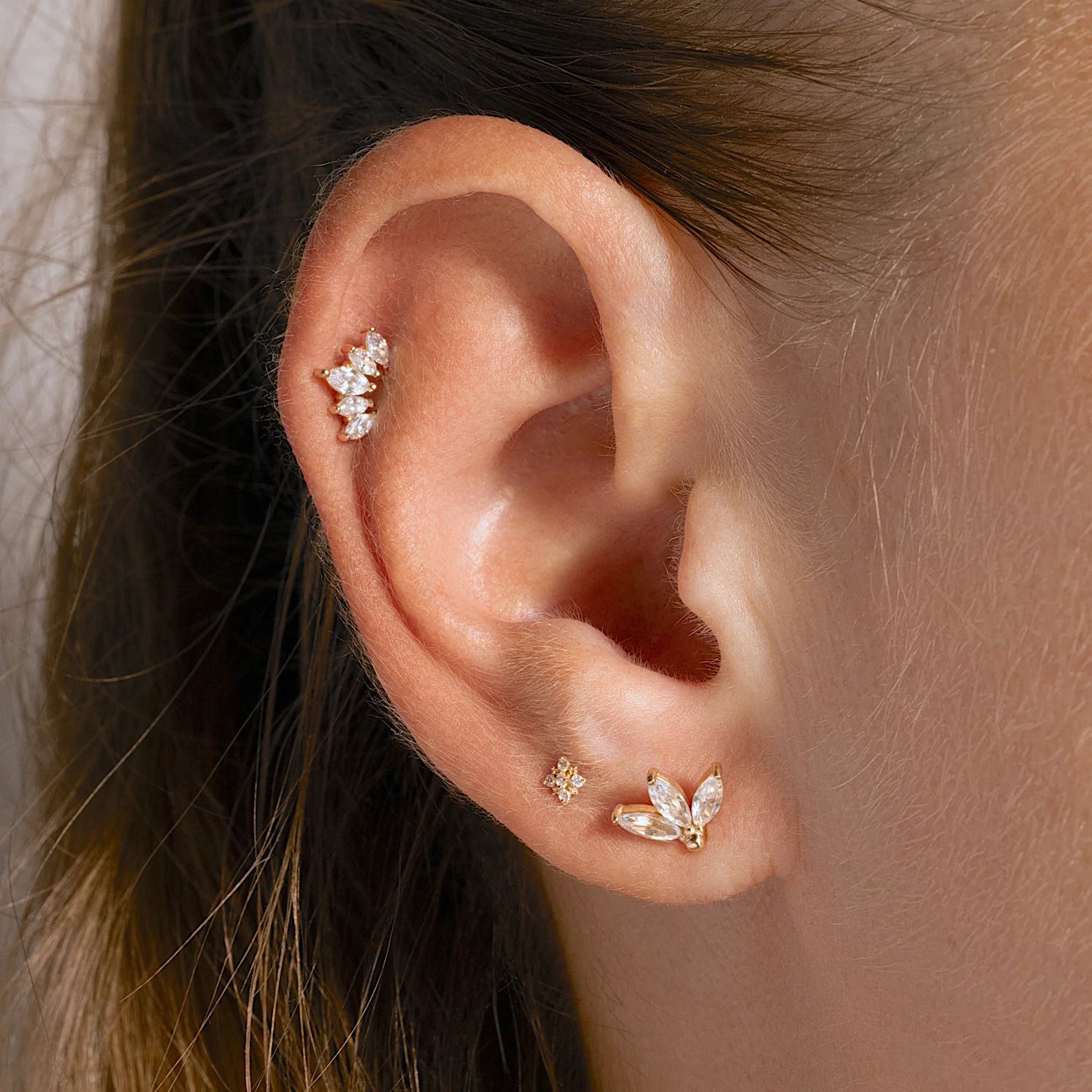 Model wearing 14K gold triple leaf stud earring, showcasing a delicate and elegant ear stack.