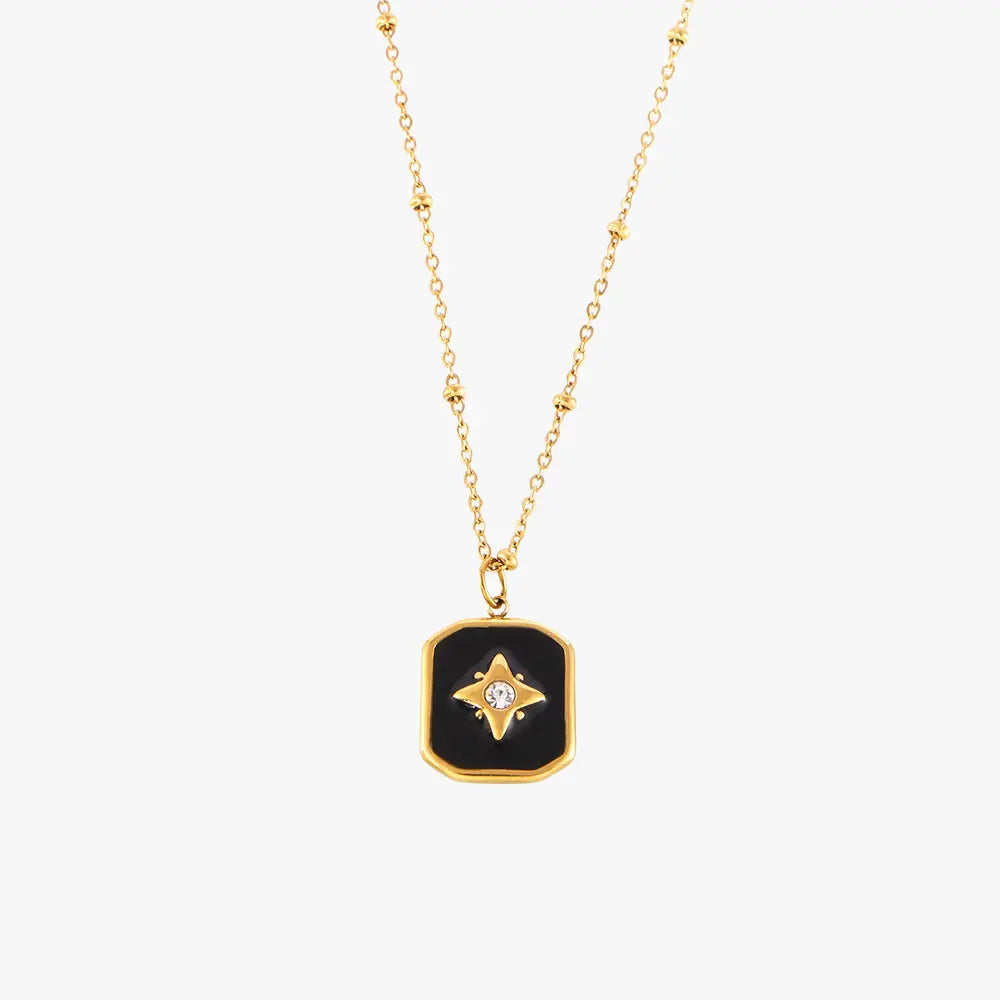 Single gold necklace with a black enamel rectangular pendant showcasing a star and crystal design on a plain white background.