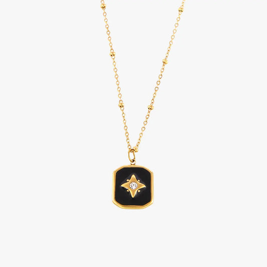 Single gold necklace with a black enamel rectangular pendant showcasing a star and crystal design on a plain white background.