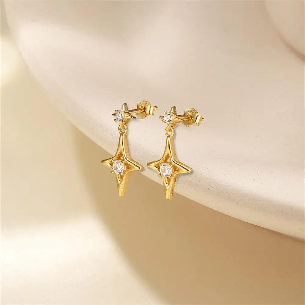 Gold star-shaped dangle earrings with sparkling crystals, displayed on a soft neutral background, featuring a celestial and elegant jewelry design.