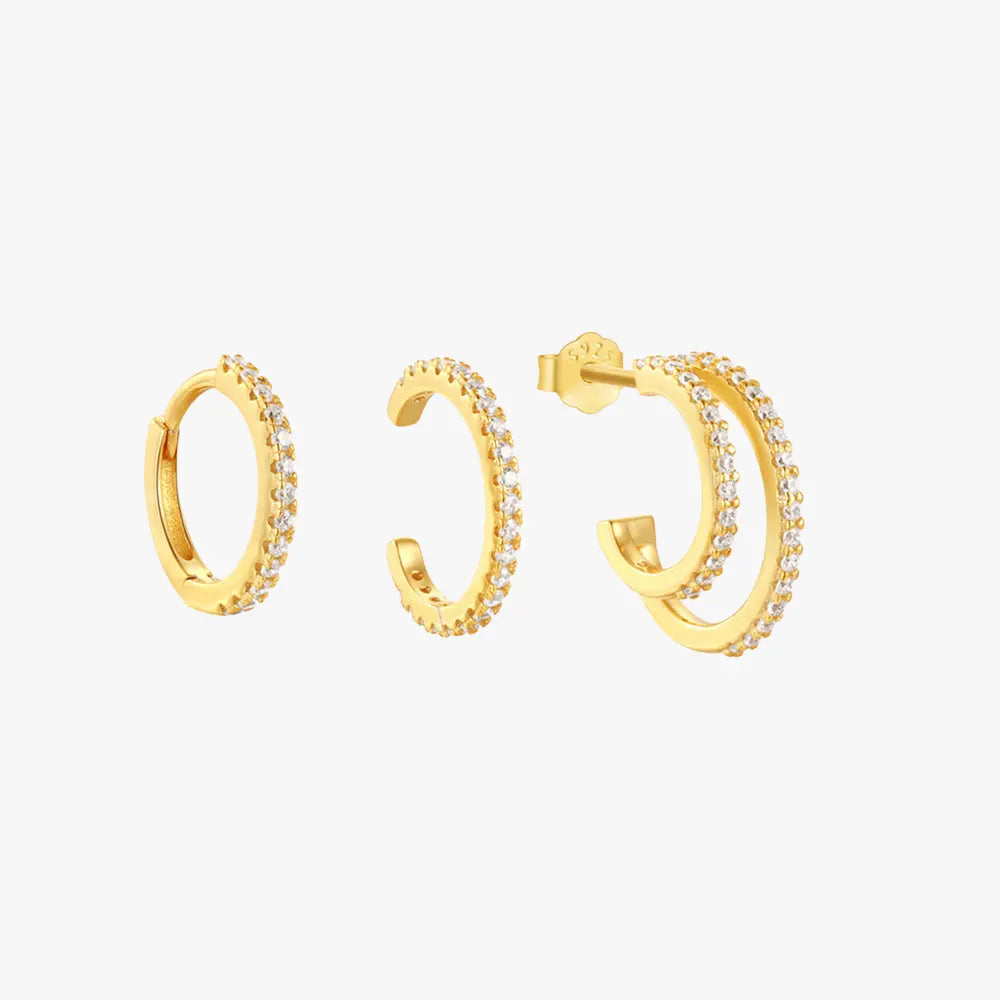 Set of three gold earrings with cubic zirconia stones, including a hoop, open cuff, and double-layered stud