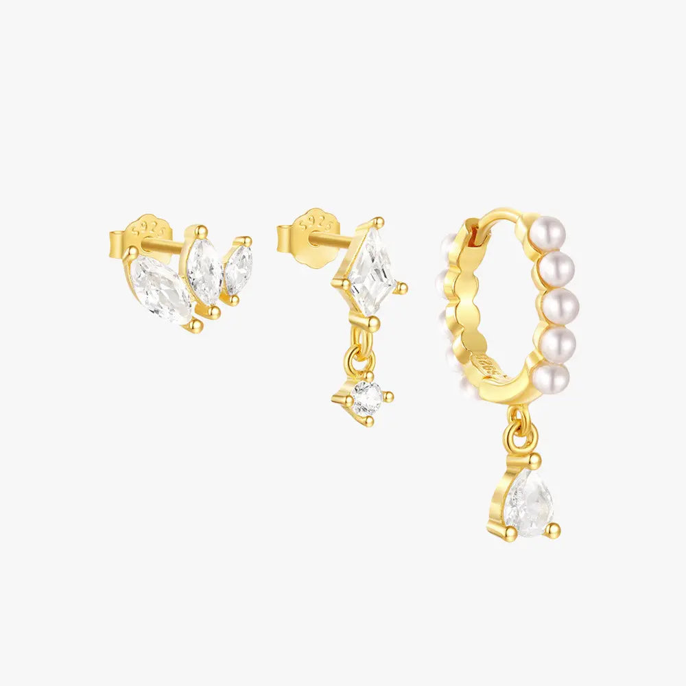 Gold-plated earring set featuring marquise-cut cubic zirconia studs, a drop diamond-shaped CZ earring, and a pearl-accented huggie hoop with a dangling teardrop crystal.