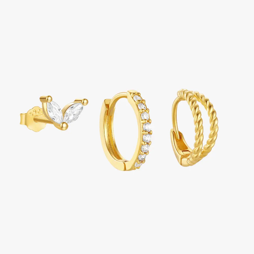 Gold earring set featuring a marquise-shaped stud with clear stones, a pave huggie hoop earring, and a twisted rope design huggie hoop.