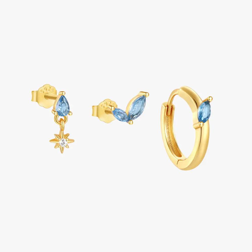 Gold and blue gemstone earring set featuring a star drop stud, marquise-cut stud, and blue gemstone hoop earring.