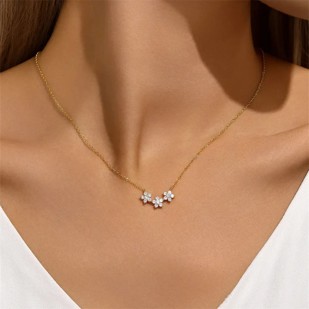 Elegant gold floral necklace with three cubic zirconia clusters, adding a touch of sparkle to any outfit, worn by a model.