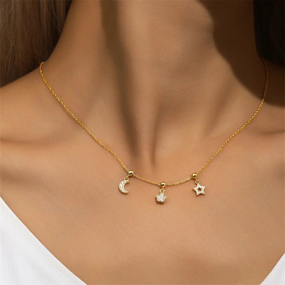 Close-up of a woman wearing a gold necklace featuring moon, star, and floral-shaped pendants.