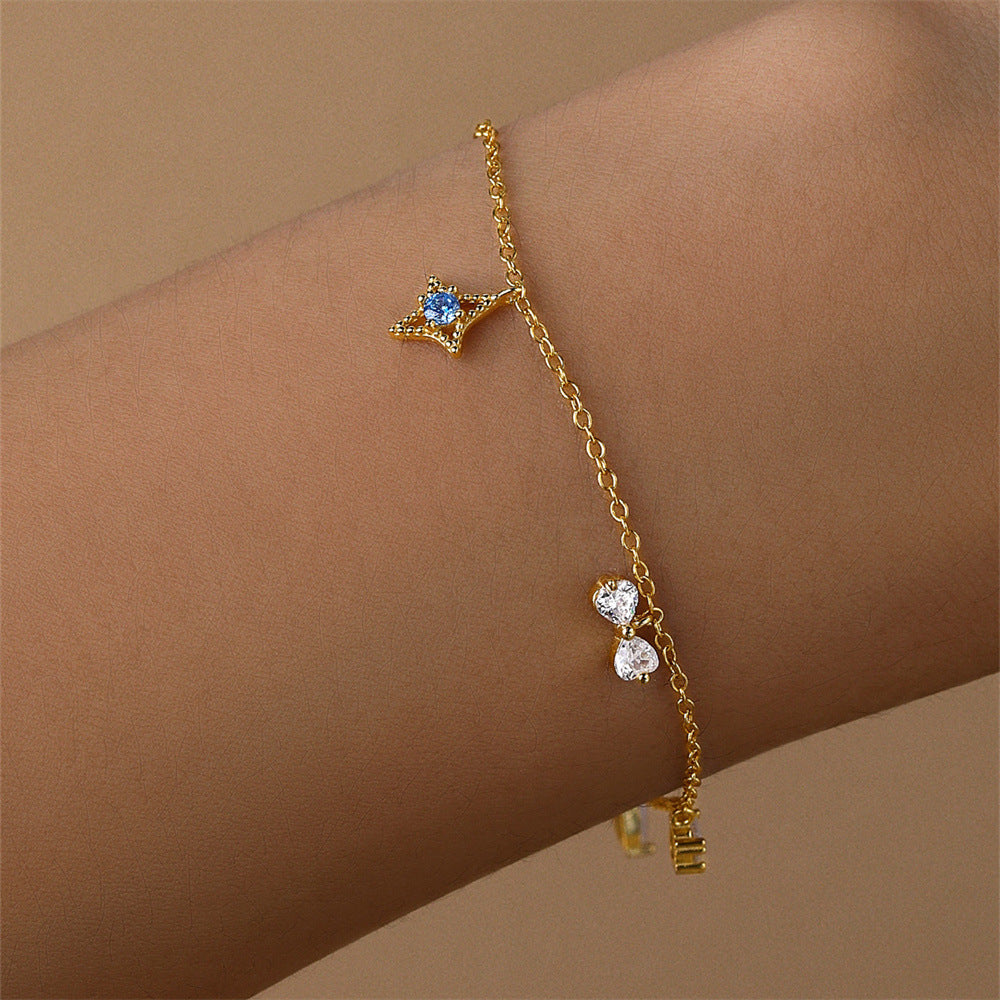 Close-up of a gold-plated sterling silver bracelet worn on a wrist, highlighting the star and crystal charms.