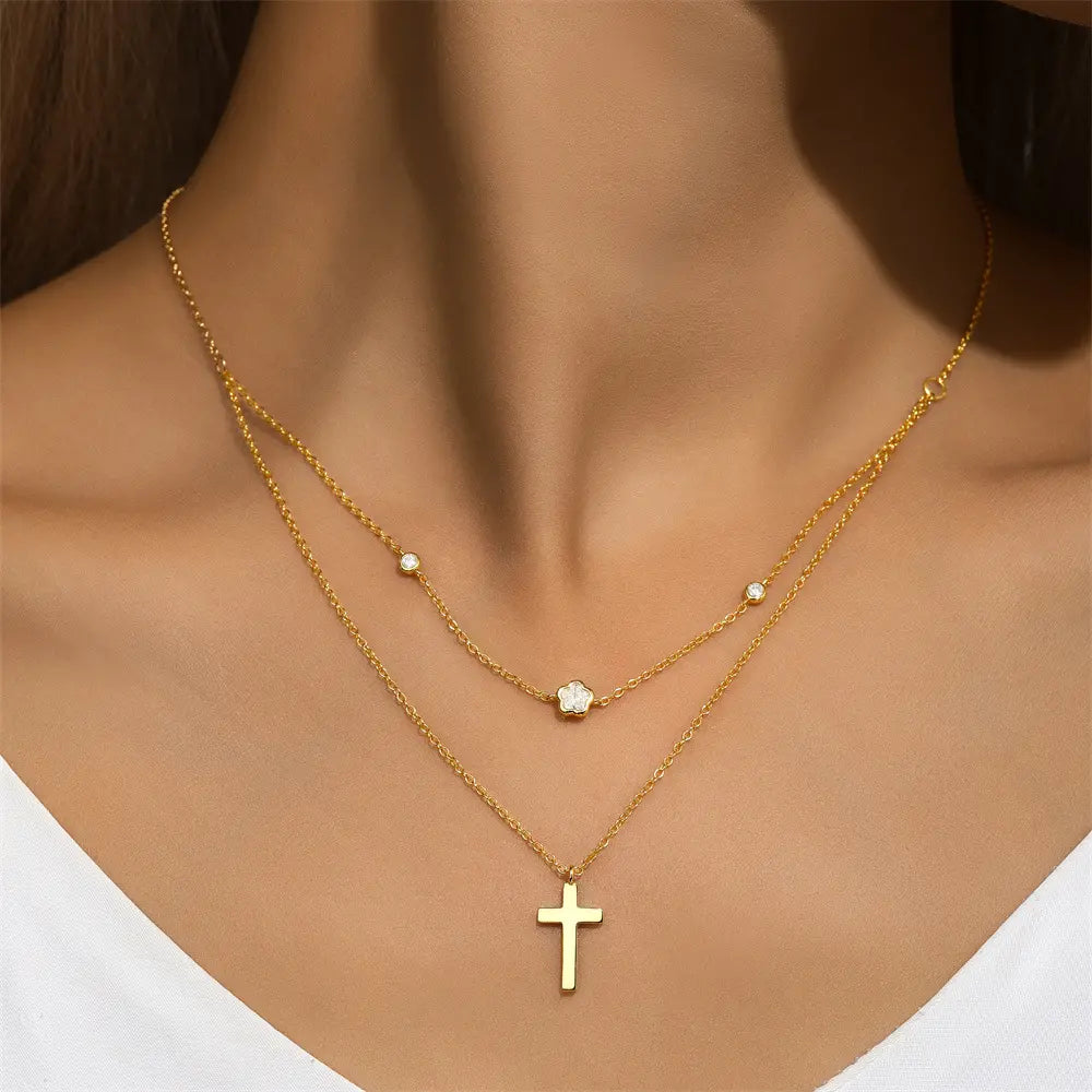 Model wearing a double-layer gold necklace with a cross pendant and floral charms, adding sophistication to any outfit.