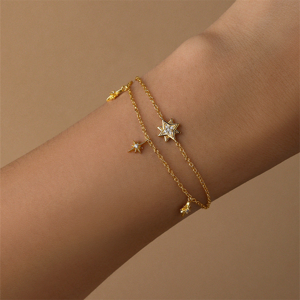 Layered gold bracelet with sparkling star charms displayed on a wrist for a stylish look.