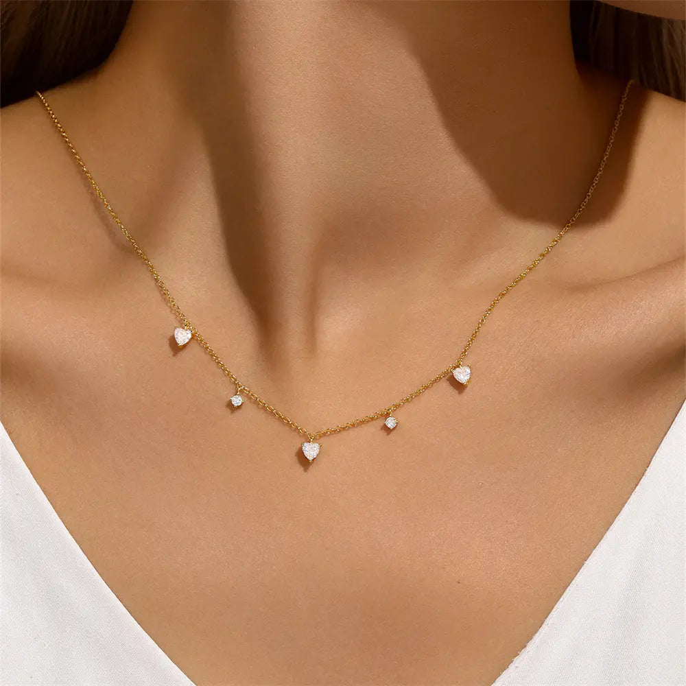 Model wearing a gold-plated heart pendant necklace with small cubic zirconia drops, perfect for an elegant and chic look.