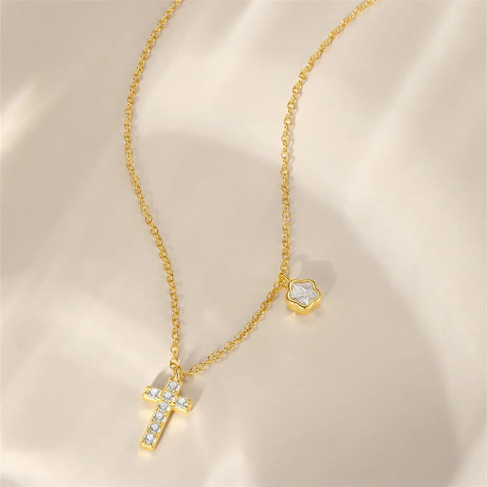 Flat lay of a gold cross necklace featuring a delicate floral charm, made with 925 sterling silver and sparkling cubic zirconia.