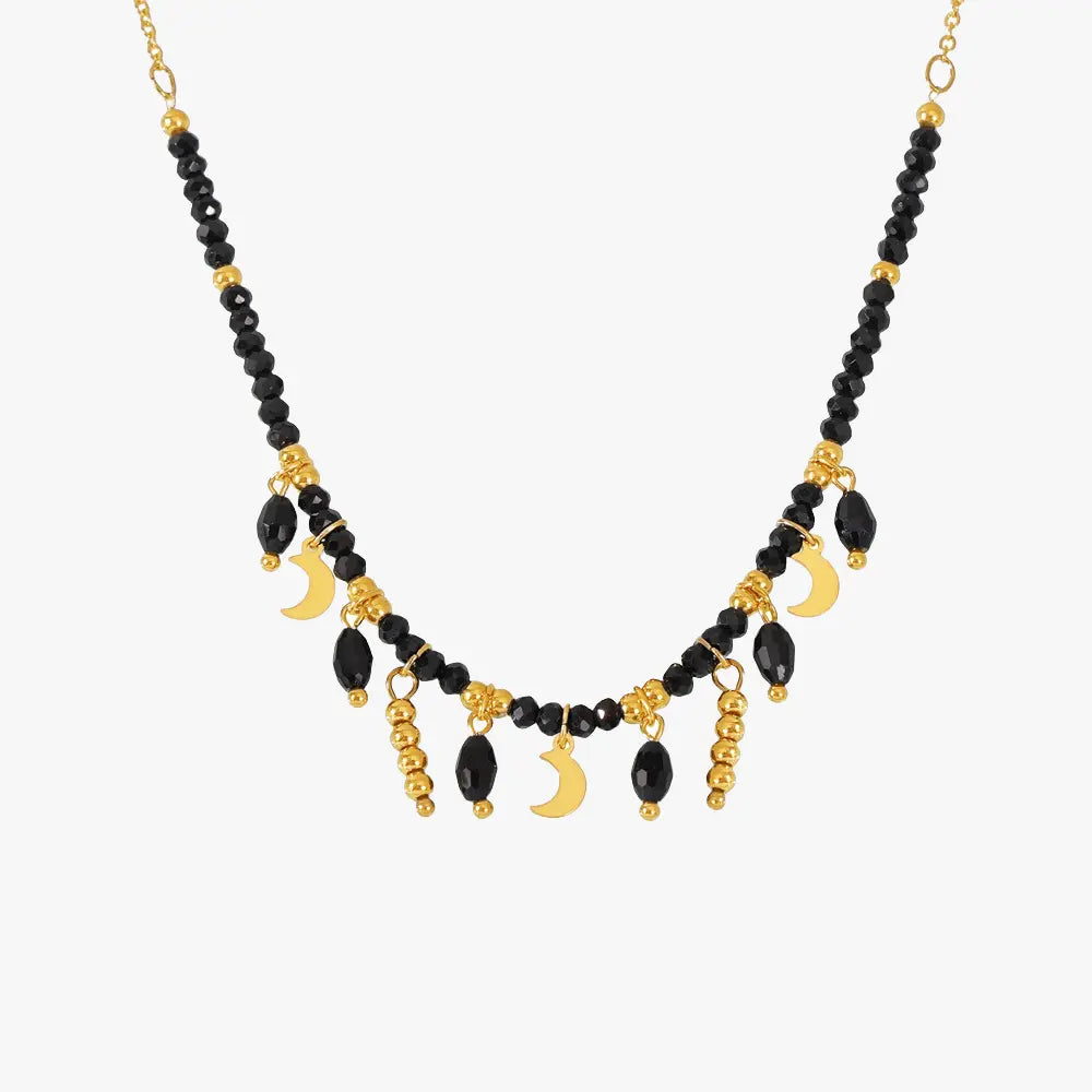 Gold-tone necklace with black beads and crescent moon pendants, elegantly designed for a bold look.