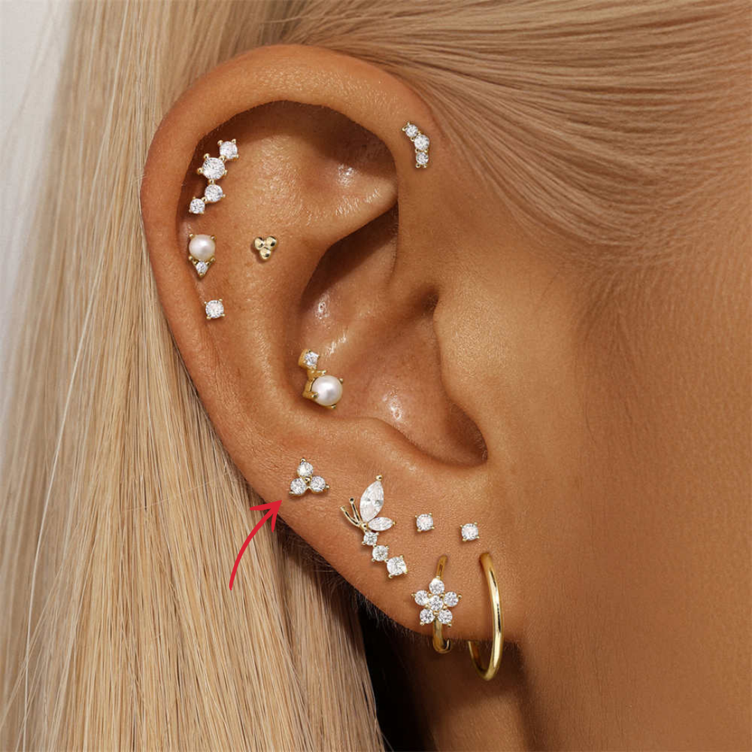 Model wearing 14K gold zirconia three-stone stud earring, stacked with other delicate pieces.