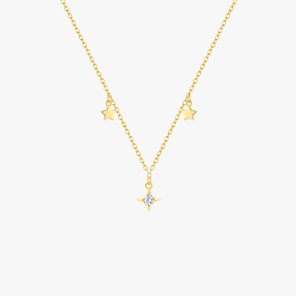 Golden star-themed necklace showcased on a neutral beige background, emphasizing its sophisticated design.