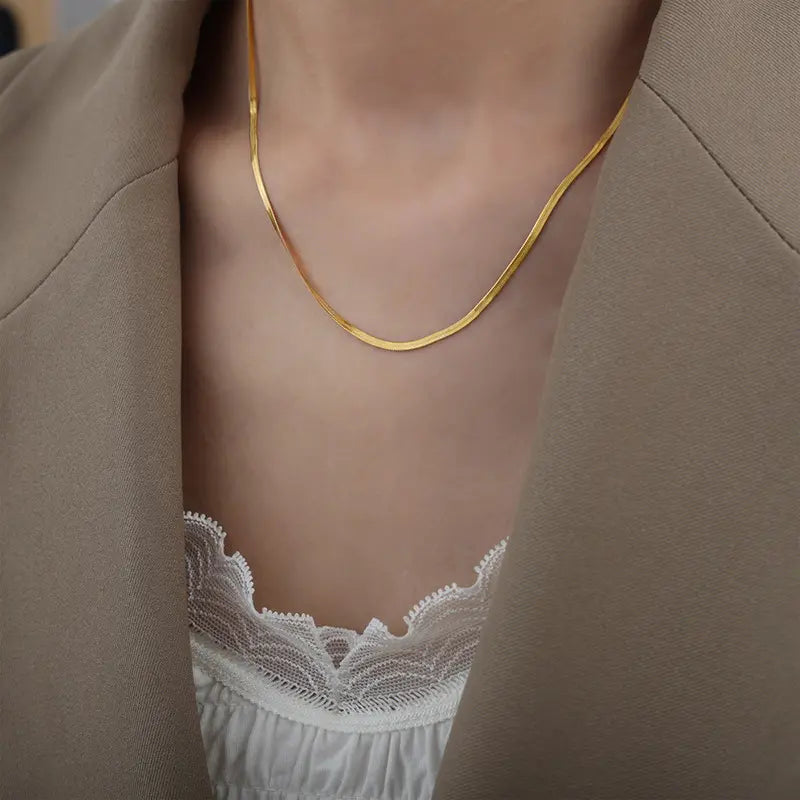 Model wearing a 14k gold-plated titanium snake chain necklace, paired with a chic outfit, showcasing its elegant design.