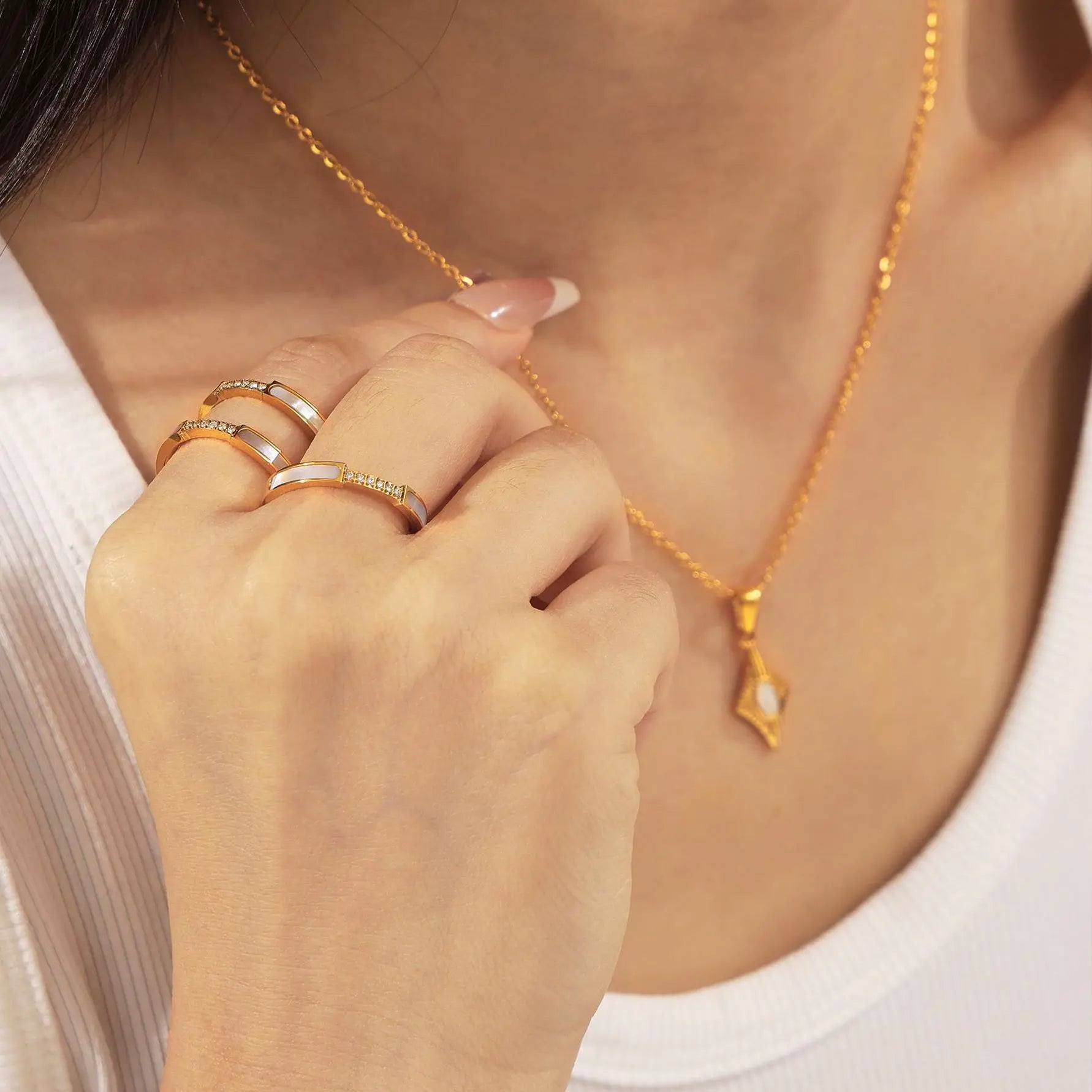 A model wearing a gold diamond-shaped pendant necklace paired with coordinating gold rings, showcasing a minimalist and elegant style.