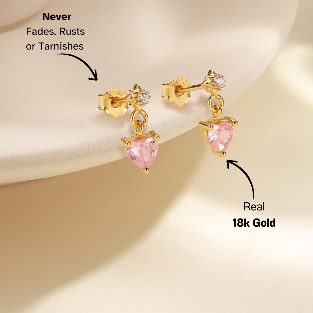 Feminine gold heart drop earrings with pink gemstone. Stylish and trendy jewelry for women.