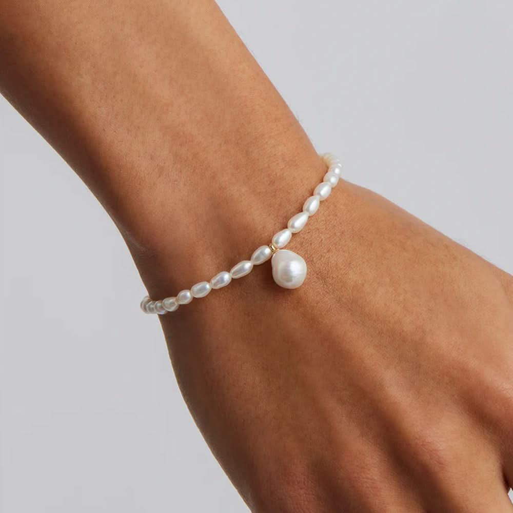 Delicate pearl bracelet with a large pearl charm displayed on the wrist, showcasing the timeless elegance.