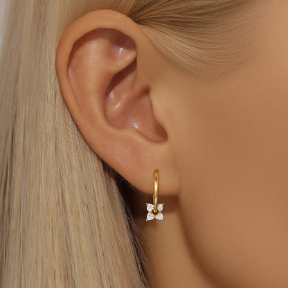 Gold floral pearl dangle earrings on a model, a chic and trendy fashion accessory.