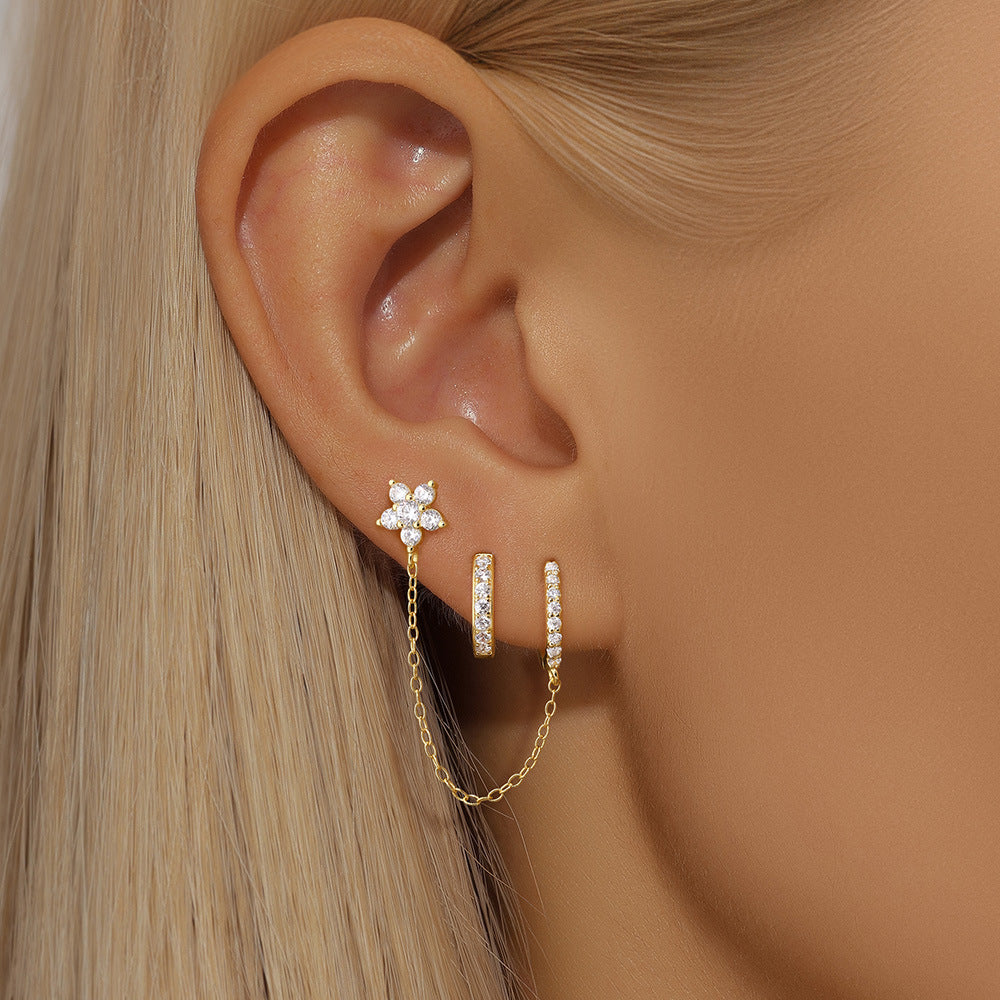 Gold flower diamond stud earrings with huggie and chain, sparkling and sophisticated design.