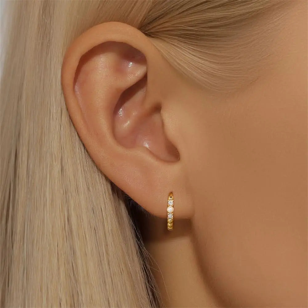 Close-up of gold hoop earrings with pearls and crystals on an ear, showcasing a classic, minimalist style