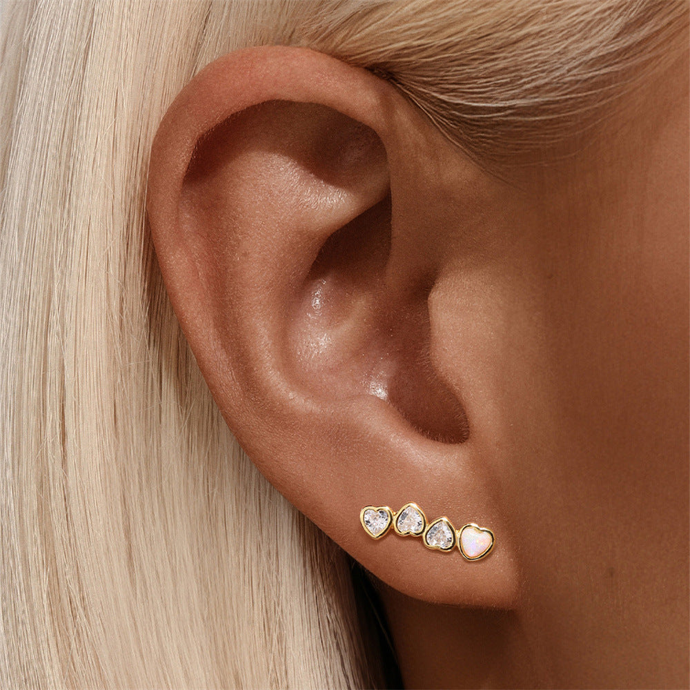 Elegant gold heart-shaped zircon earrings worn on ear, minimalist and stylish jewelry for women.