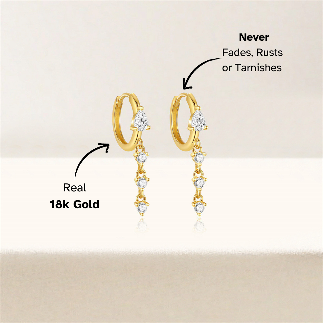 Minimalist display of gold huggie hoop earrings featuring sparkling teardrop CZ stones, ideal for a sophisticated ear stack.