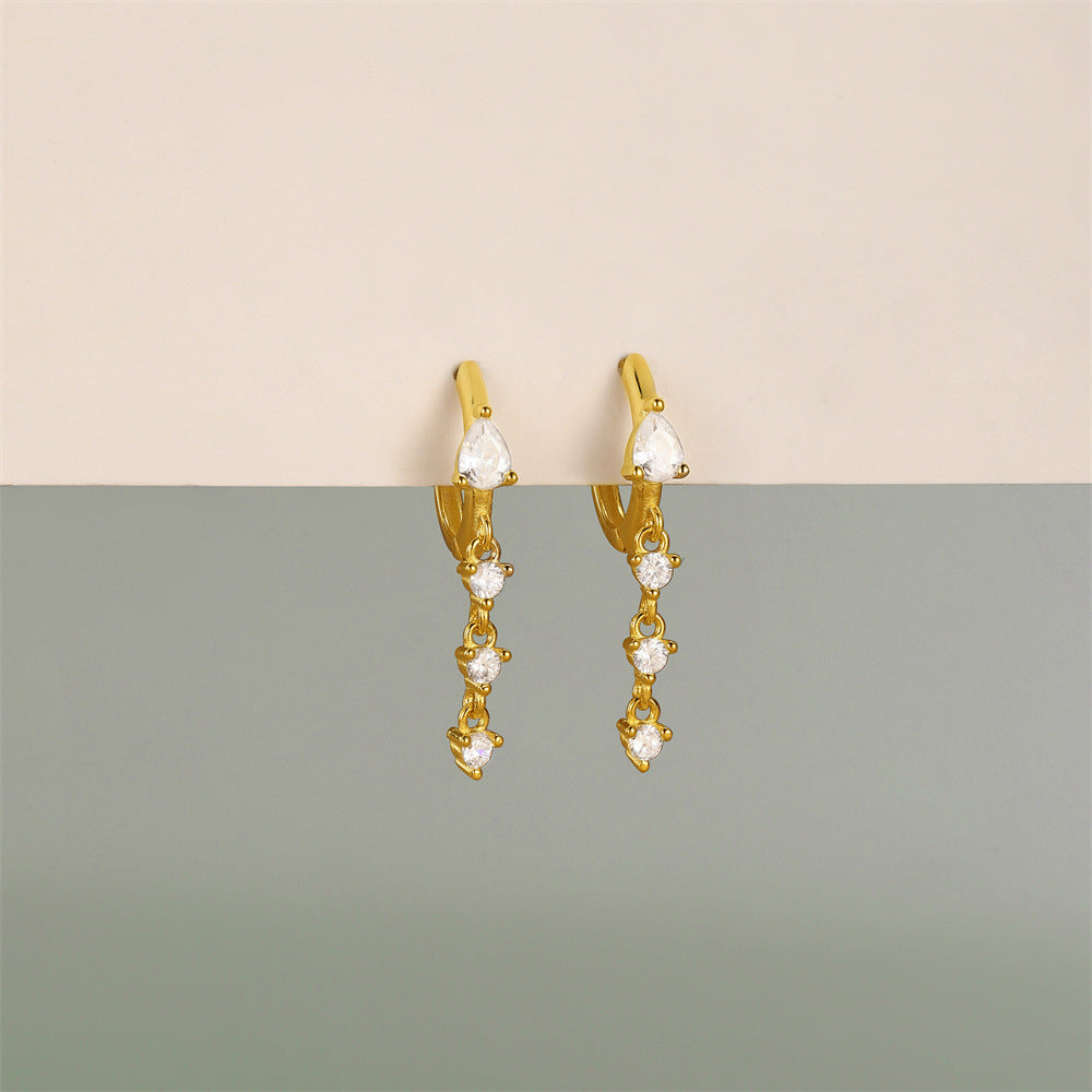 Delicate gold huggie hoop earrings with dangling teardrop-shaped cubic zirconia stones, great for a chic and modern style.