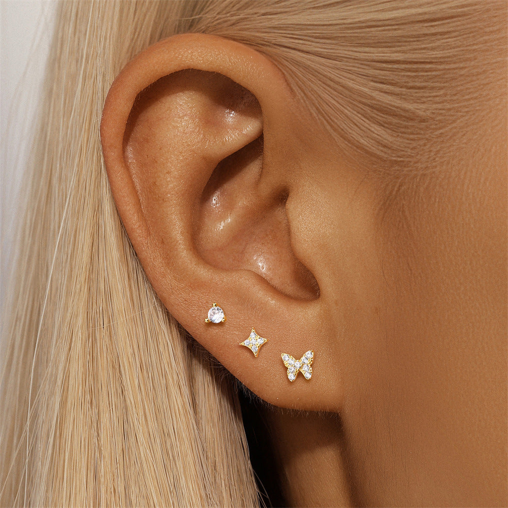 Model wearing a 3-piece gold stud earring set with star, butterfly, and CZ round design for an elegant ear stack.