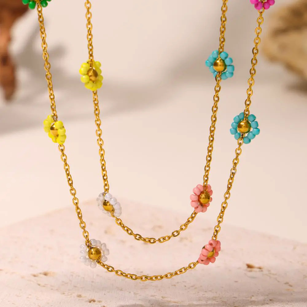 Layered gold necklace featuring multicolor beaded flower charms on a display.