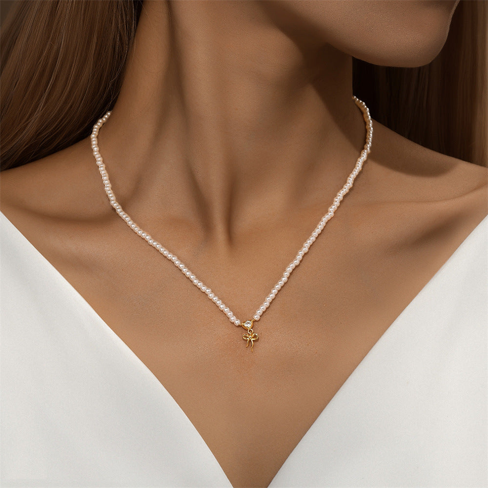 pearl-necklace-with-gold-charm-on-model.png – Beautiful pearl necklace adorned with a 14k gold bow charm, styled on a model to showcase its elegance and versatility for any occasion.