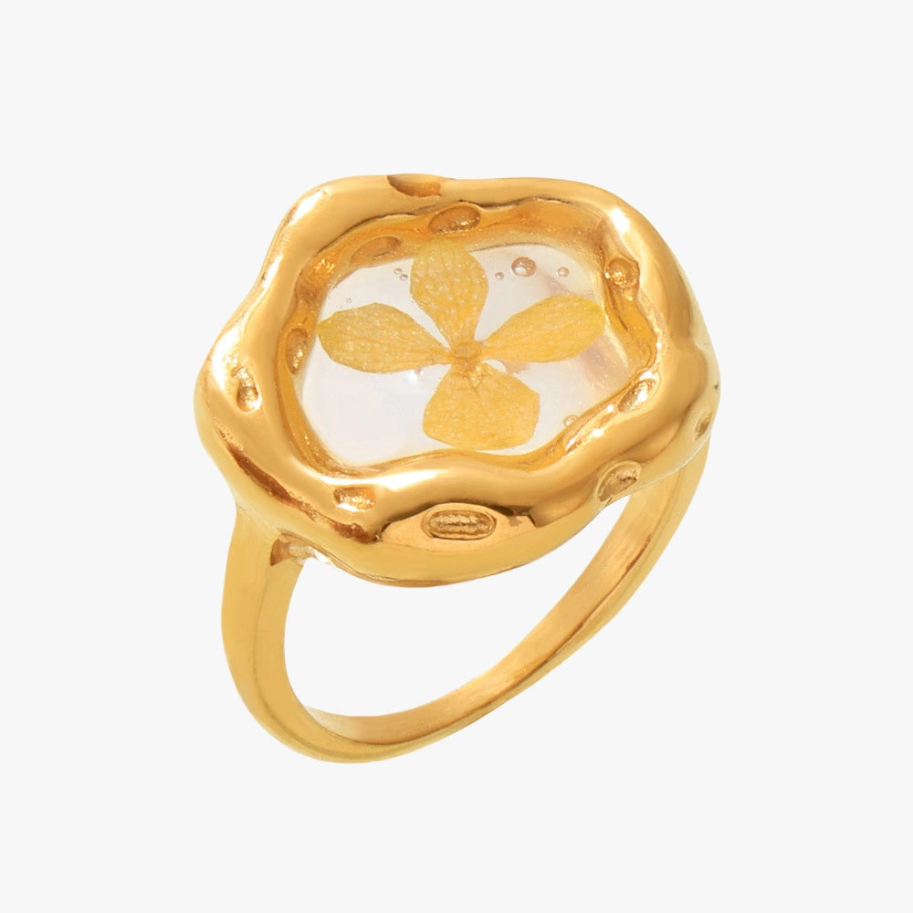 Close-up of a yellow floral resin ring with a single dried flower encased in gold resin.